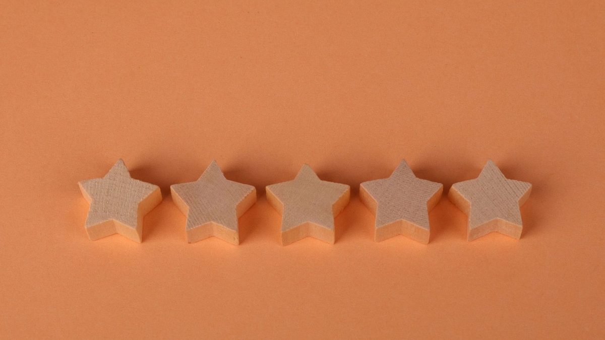 Cinq étoiles en bois clair alignées sur un fond orange uni.